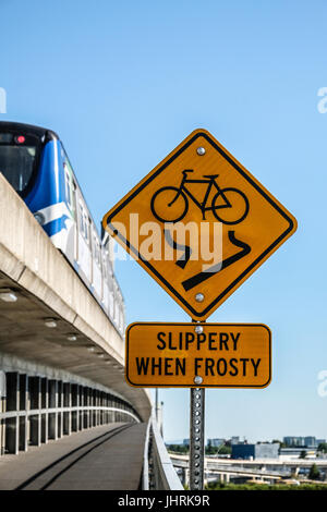 A Slippery When Frosty sign and a skytrain on North Arm Canada Line skytrain bridge over the Fraser river between Richmond and Vancouver Stock Photo