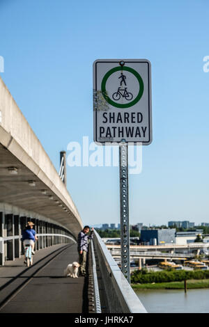 A Shared Pathway sign and a boy with his dog walking on North Arm Canada Line skytrain bridge over the Fraser river between Richmond and Vancouver Stock Photo