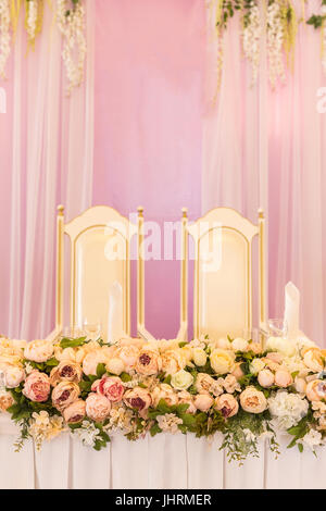 festive table for the bride and groom decorated with pink cloth and flowers. Wedding table decor concept. Stock Photo
