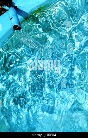 Swirling cyan blue water with light waves and spots.  Fragment of a fountain in german park with faucet. Selected focus. Stock Photo
