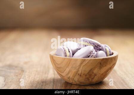 violet macarons in wood bowl on wooden table Stock Photo