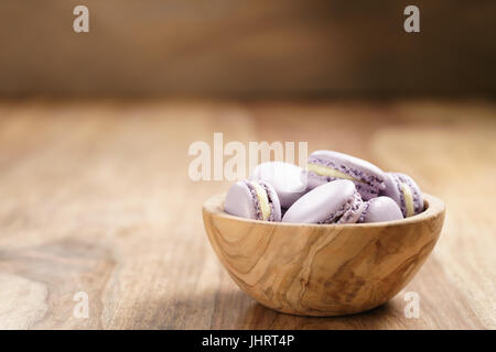 violet macarons in wood bowl on wooden table Stock Photo