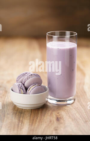 violet macarons in white bowl with blueberry yogurt on wooden table Stock Photo