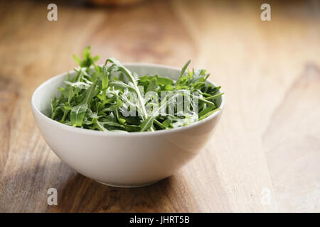 fresh green rocket salad arugula leaves in white bowl Stock Photo