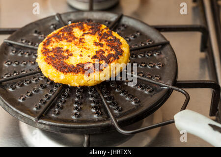 Traditional Colombian Arepa de Choclo Preparation : Corn bread being roasted on a round grill Stock Photo