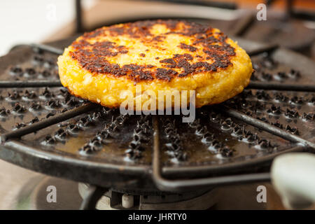 Traditional Colombian Arepa de Choclo Preparation : Corn bread being roasted on a round grill Stock Photo