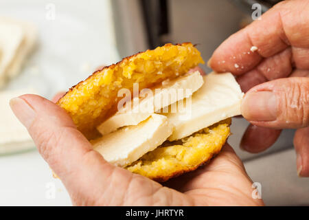 Traditional Colombian Arepa de Choclo Preparation : Stuffing the cooked corn bread with cheese Stock Photo