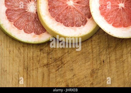 Photograph of some grapefruit slices on wood cutting board Stock Photo
