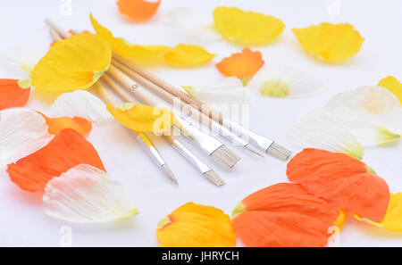 Colored abstraction of brushes for drawing. Flower leaves with gouache on white table. Stock Photo