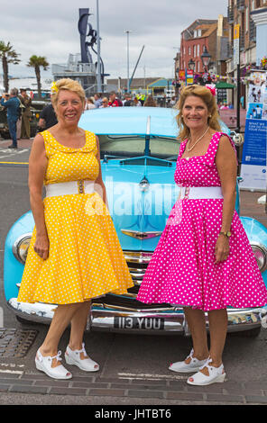 Poole Goes Vintage, Poole, Dorset, UK. 16th July 2017. Poole Goes Vintage Event takes place on the Quay - visitors dress up in vintage clothes. Ladies in polka dot dresses pose in front of Chevrolet fleetline car. Credit: Carolyn Jenkins/Alamy Live News Stock Photo