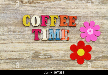 Coffee time written with colorful wooden letters on wooden surface and two flowers Stock Photo