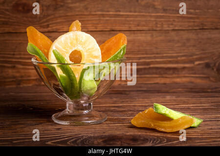 Candied pineapple, melon, kiwi in a bowl on a wooden background on a wooden background Stock Photo