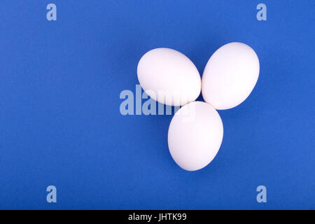 three white eggs on a blue background Stock Photo