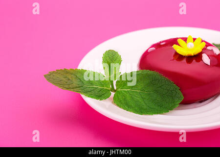Sweet red cake with yellow flower and mint leaves. On a pink background. Birthday dessert. Stock Photo