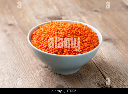 Red lentils in blue bowl on old wooden background Stock Photo