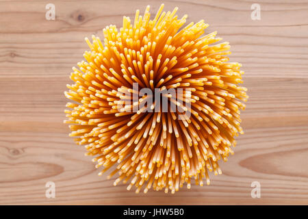 Bunch of raw spaghetti standing on a wooden surface Stock Photo