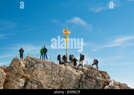 GARMISCH - JULY 04: Summit of the Zugspitze, Germany with some tourists around the golden cross on July 04, 2016. Stock Photo
