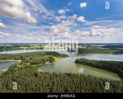 Aerial view of green islands and clouds at summer sunny morning. Masurian Lake District  in Poland. Wonders of the world from above. Yachts sailing in