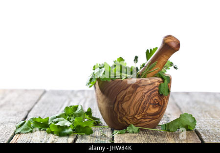 Different herbs on a old wooden table . Wooden mortar with rosemary, coriander, thyme and parsley.Isolated on white background. Stock Photo