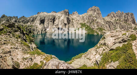 Dramatic rock formations surrounding the turquoise Lac de Capitello in the mountains above Restonica near Corte in Corsica Stock Photo