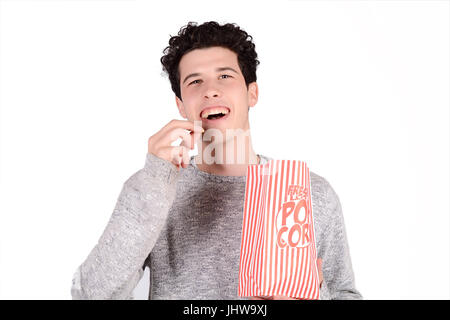 Portrait of young man eating popcorn. Isolated white background. Stock Photo