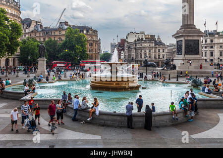 Tourists and locals, families and friends around a fountain in Trafalgar Square in central London, England. Stock Photo