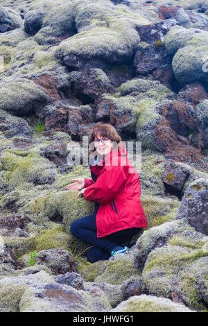 Female tourist amazed at the thickness of moss growing on the Eldhraun Lava Field in Iceland Stock Photo