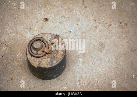 Old antique weight, 5 kg, on dirty grunge floor. Stock Photo