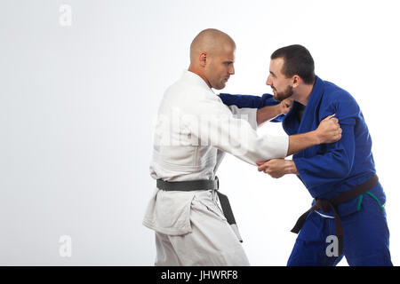 Two young men in a blue and white kimono doing a judo shot,  fight judo , Jiu Jitsu on an isolated white background Stock Photo