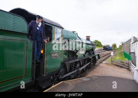 The driver of ex-GWR loco 6960 'Raveningham Hall' waits to leave Washford station with a Bishops Lydeard train, West Somerset Railway, UK