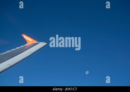View of Easy Jet airplane wing from the window, blue sky and moon