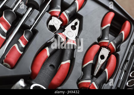 Black-red pliers and screwdrivers in the dark toolbox. Closeup top view photo. Horizontal. Stock Photo