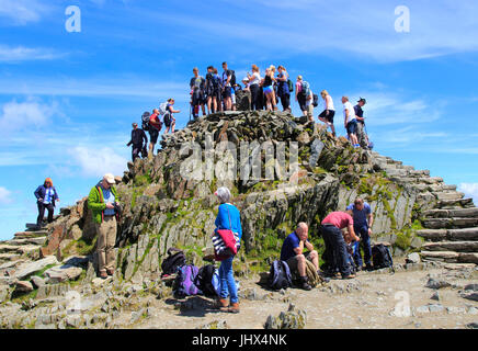 Walkers crowd onto the summit point, Mount Snowdon, Gwynedd, Snowdonia, north Wales, UK Stock Photo