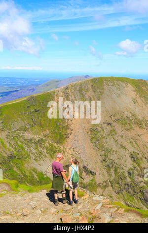 Man and woman enjoying view from summit of Mount Snowdon, Gwynedd, Snowdonia, north Wales, UK Stock Photo