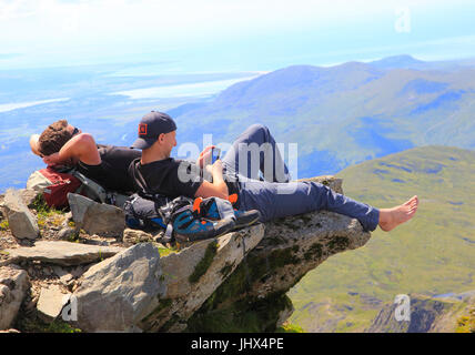 Two male walkers resting on rock overhang, Mount Snowdon, Gwynedd, Snowdonia, north Wales, UK Stock Photo