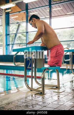 Quadriplegic swimmer ready to dive in. He is getting on the platform with goggles on. Stock Photo