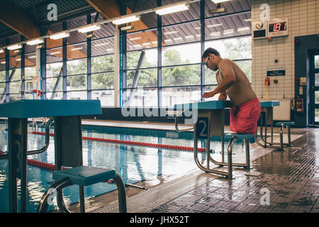 Quadriplegic swimmer ready to dive in. He is getting on the platform with goggles on. Stock Photo