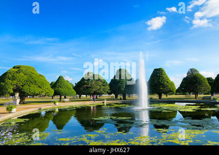 A couple take a stroll round The Great Fountain Garden surrounded by ancient yew trees on a perfect summer's afternoon, Hampton Court Palace Gardens Stock Photo