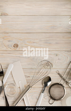 Kitchen tools of white and steel color (accessories) for baking on a light wooden background. Selective focus. Stock Photo