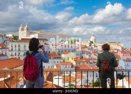 Lisbon Alfama, a woman takes a photo of the Alfama skyline from the viewing terrace of the Largo das Portas do Sol, high up in the old town, Lisbon. Stock Photo