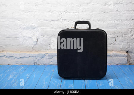 Retro style - Vintage black suitcase on a wood and brick background. Stock Photo