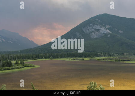 Forest fire smoke & ash changes the previously blue / green waters of Vermillion Lake, Banff National Park, Canada. The nearby forest fire left the lakes un recognisable as they changed from a lovely blue / green to a more brown colour and the sky became full of smoke & haze. Picture taken from the Trans Canada Highway overlooking Vermillion Lakes near Banff town, brown smoke & ash filled the sky from Saturday night onwards, by Sunday the lake had completely changed colour. Motorists stopped to look in disbelief at the drastic change to the lake. Fire believed to have started in Verdant Creek Stock Photo