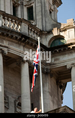 Belfast, UK. 17th July, 2017.  The Union Flag is hoisted up the flag pole on Belfast City hall to Commemorate The Duchess of Cornwall's 70th Birthday. Credit: Bonzo/Alamy Live News Stock Photo