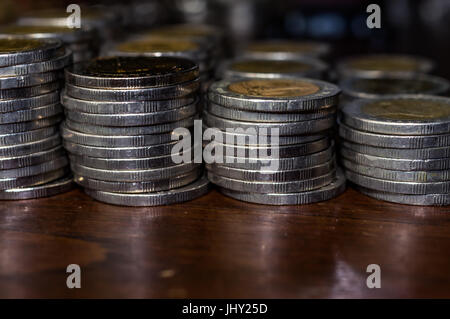 stacks of coins, small change on wooden table surface Stock Photo