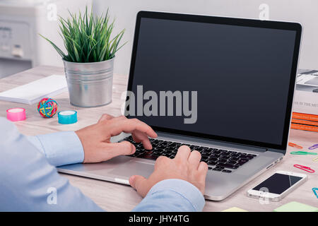 Man working with laptop. Mans hands on laptop computer. Businessman at workplace keyboarding on laptop with blank screen mockup. Stock Photo