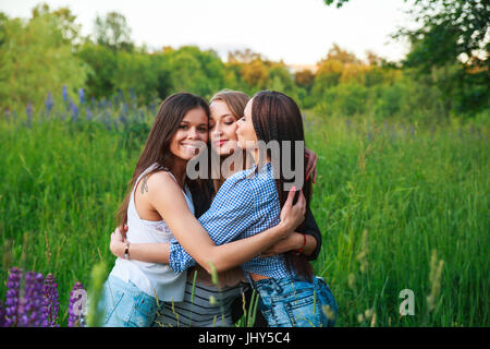 Girlfriends Friendship Happiness Community Concept. Three smiling friends hugging outdoors in the nature Stock Photo