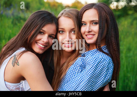 Girlfriends Friendship Happiness Community Concept. Three smiling friends hugging outdoors in the nature Stock Photo