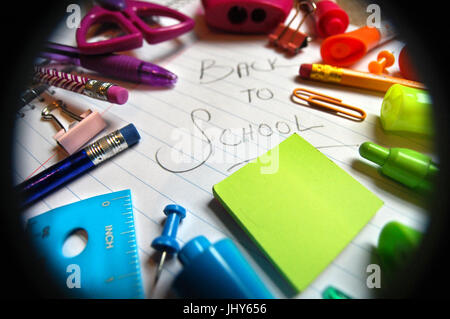 A colorful array of school supplies scattered around a wide-ruled notebook. Stock Photo