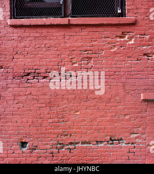 red painted brick building wall window ledge chipped broken bricks Stock Photo