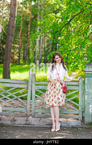 Portrait of beautiful young women standing against a fence looking at camera while eating ice cream. Stock Photo